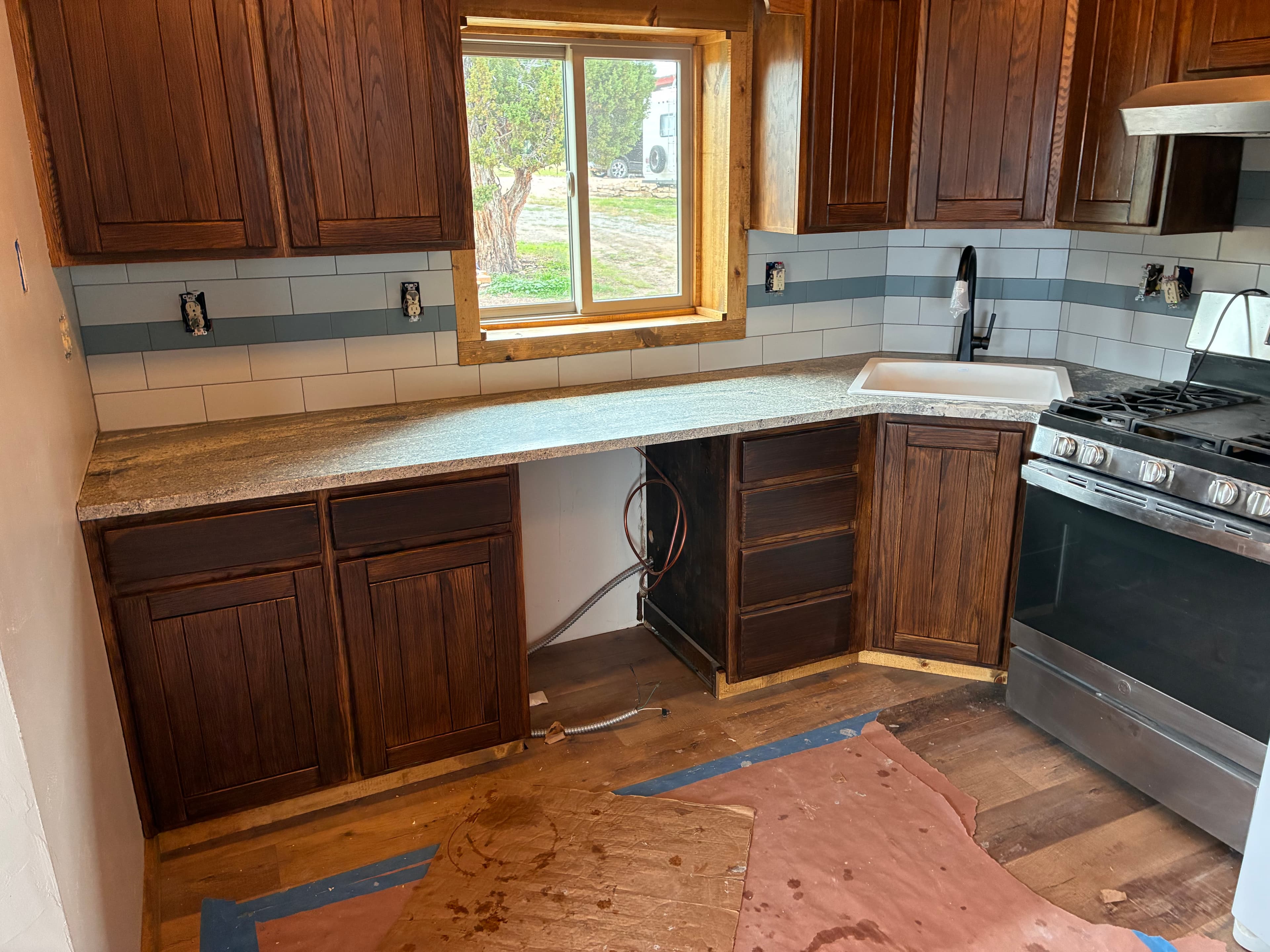 Kitchen renovation with dark wood cabinets, granite countertops, and a white subway tile backsplash.